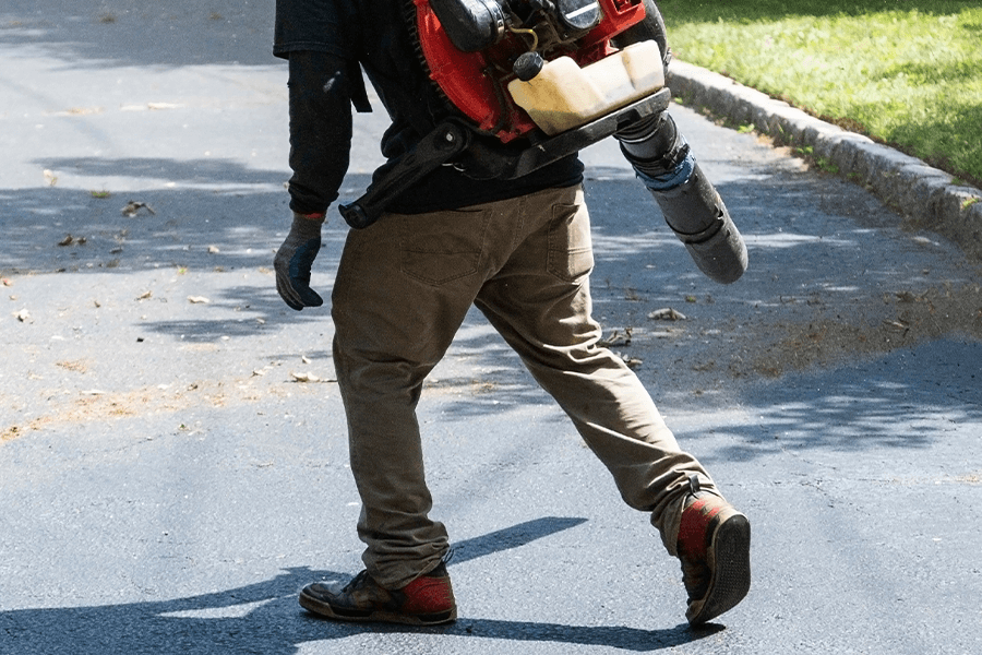 Clearing away debris with leaf blower to prep for driveway resealing - Belleville, IL