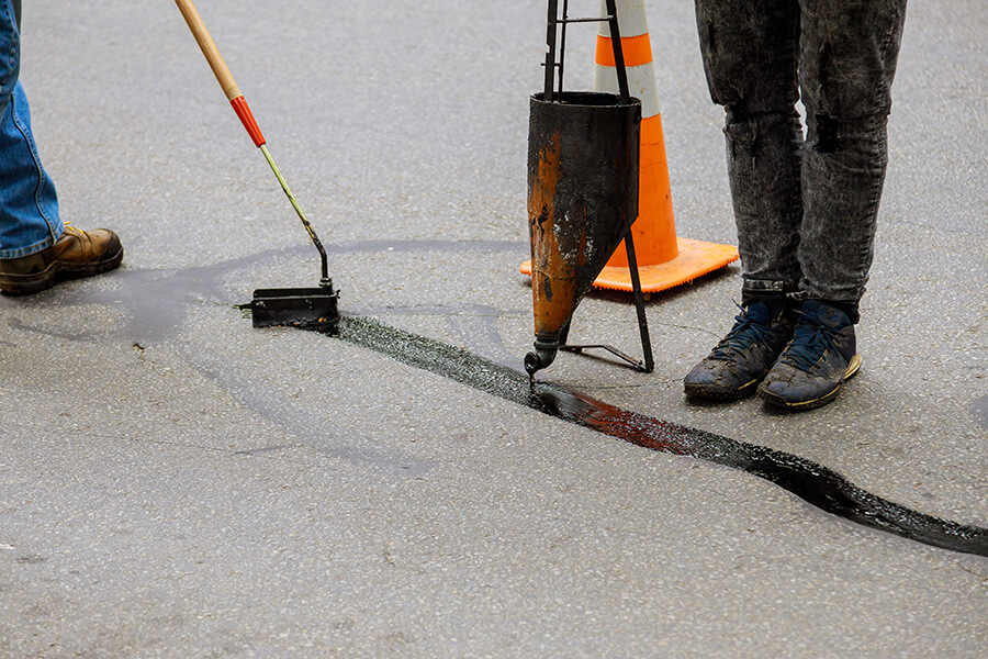 pouring hot asphalt into cracked driveway to repair the damamge - Belleville, IL